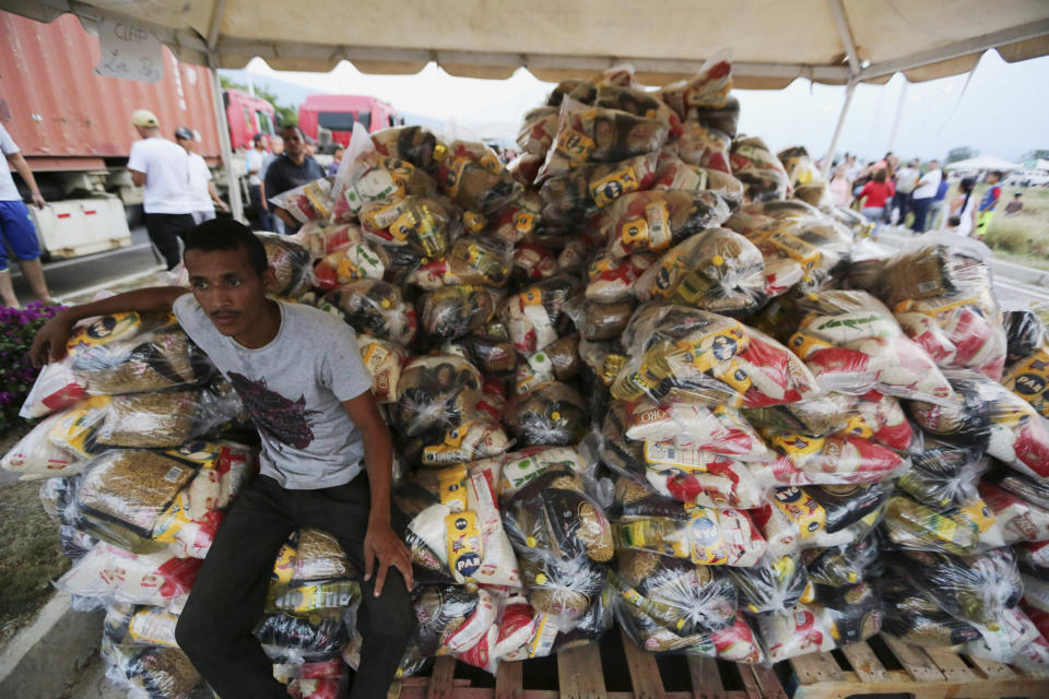 A volunteer takes a break during the distribution of bags with food subsidized by the Nicolas Maduro's government near the international bridge of Tienditas on the outskirts of Urena, Venezuela, Monday, Feb. 11, 2019. Nearly three weeks after the Trump administration backed an all-out effort to force out President Nicolas Maduro, the embattled socialist leader is holding strong and defying predictions of an imminent demise. (AP Photo/Fernando Llano)