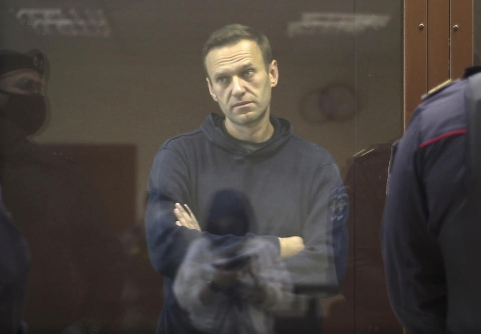 In this image made from video provided by the Babuskinsky District Court, Russian opposition leader Alexei Navalny stands in a cage during a hearing on his charges for defamation, in the Babuskinsky District Court in Moscow, Russia, Friday, Feb. 5, 2021. Navalny was accused of slandering a World War II veteran featured in the video promoting the constitutional reform allowing to extend President Vladimir Putin's rule. The politician slammed people in the video as "corrupt stooges" and "traitors." (Babuskinsky District Court via AP)