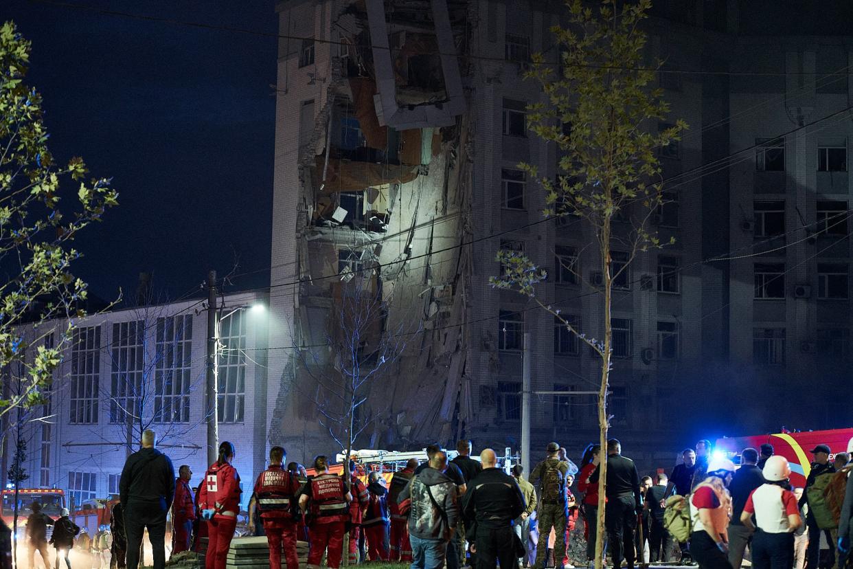 Rescuers stand outside a residential building partially destroyed after missiles strike in Dnipro (AFP via Getty Images)