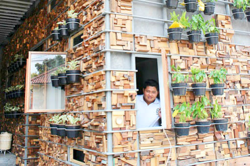 See me: Security guard Wahyu peers through a window with an outside wall designed with timber off cuts.