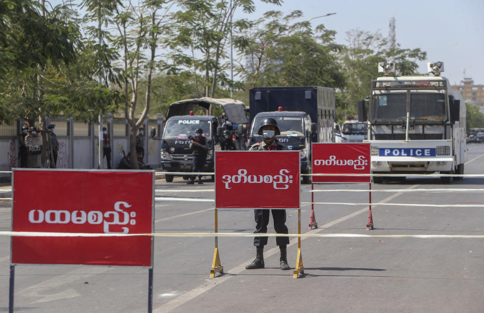 Police stand guard on a cordoned-off road, the site of clashes between the protesters and police a day earlier, in Mandalay, Myanmar on Wednesday, Feb. 10, 2021. Protesters continued to gather Wednesday morning in Mandalay breaching Myanmar's new military rulers' decrees that effectively banned peaceful public protests in the country's two biggest cities. (AP Photo)