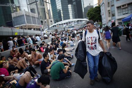 A man picks up garbage along an area blocked by protesters outside of the government headquarters building in Hong Kong, October 1, 2014. REUTERS/Carlos Barria