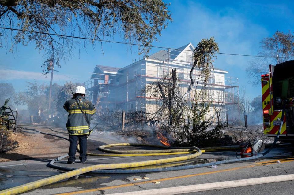 Firefighters work to save a house on U Street near 28th Street in Rio Linda during a vegetation fire on Monday, Sept. 27, 2021.