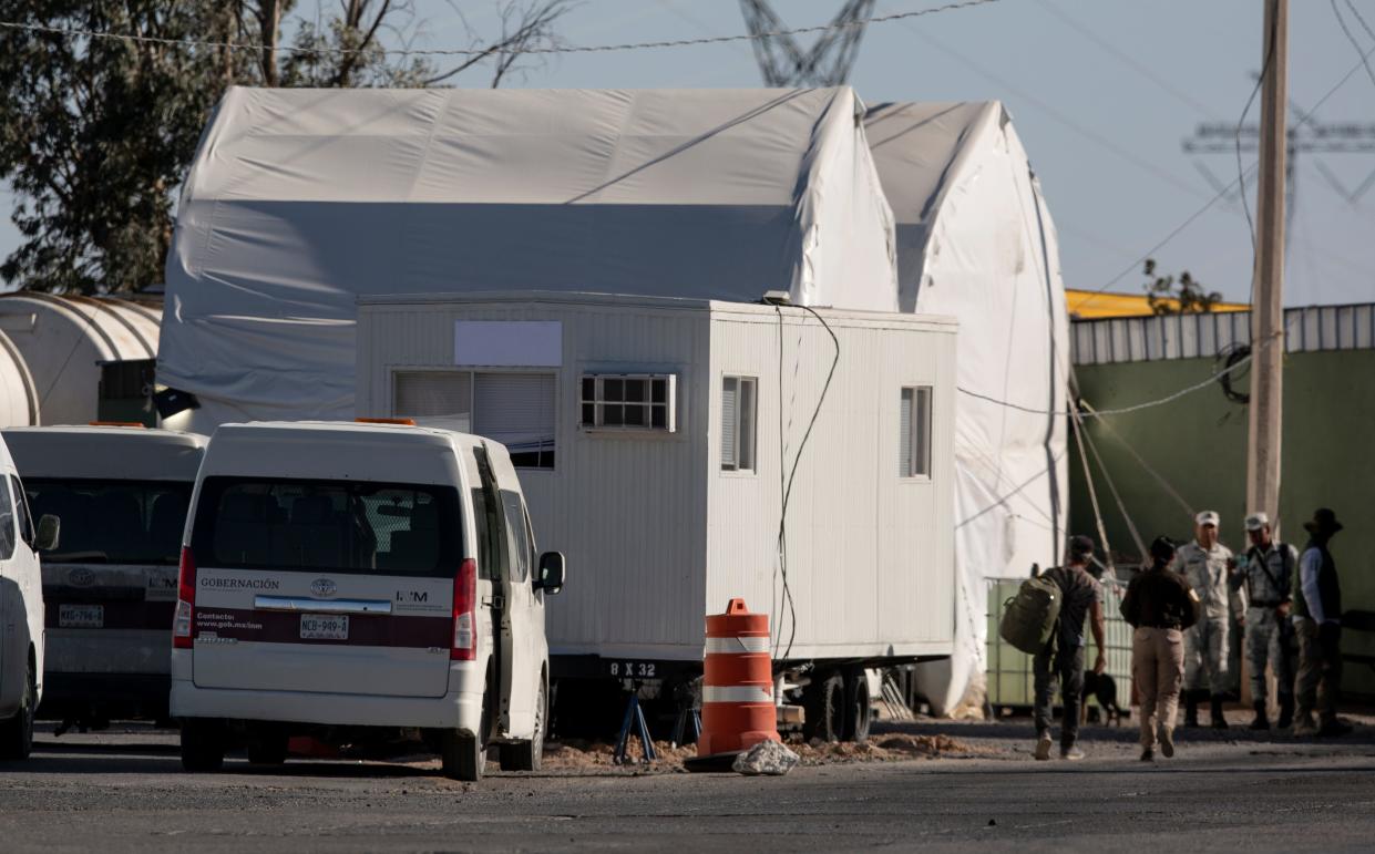 A Mexican immigration officer leads a migrant on the outskirts of Ciudad Juarez to the tent where migrants are processed before being bused to the interior of Mexico on April 24, 2024.