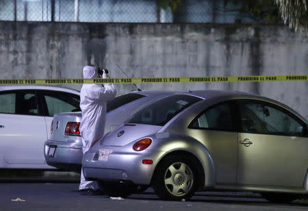 A forensic technician takes pictures at a crime scene, where men were killed inside a home by unknown assailants, in the municipality of San Nicolas de los Garza, Mexico, January 27, 2018. Picture taken January 27, 2018. REUTERS/Jorge Lopez