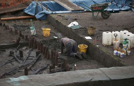 An archaeologist from the University of Cambridge Archaeological Unit, uncovers Bronze Age wooden houses, preserved in silt, from a quarry near Peterborough, Britain, January 12, 2016. REUTERS/Peter Nicholls