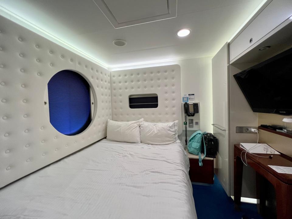 Norwegian Getaway studio stateroom interior. full bed with white cushioned paneling around it
