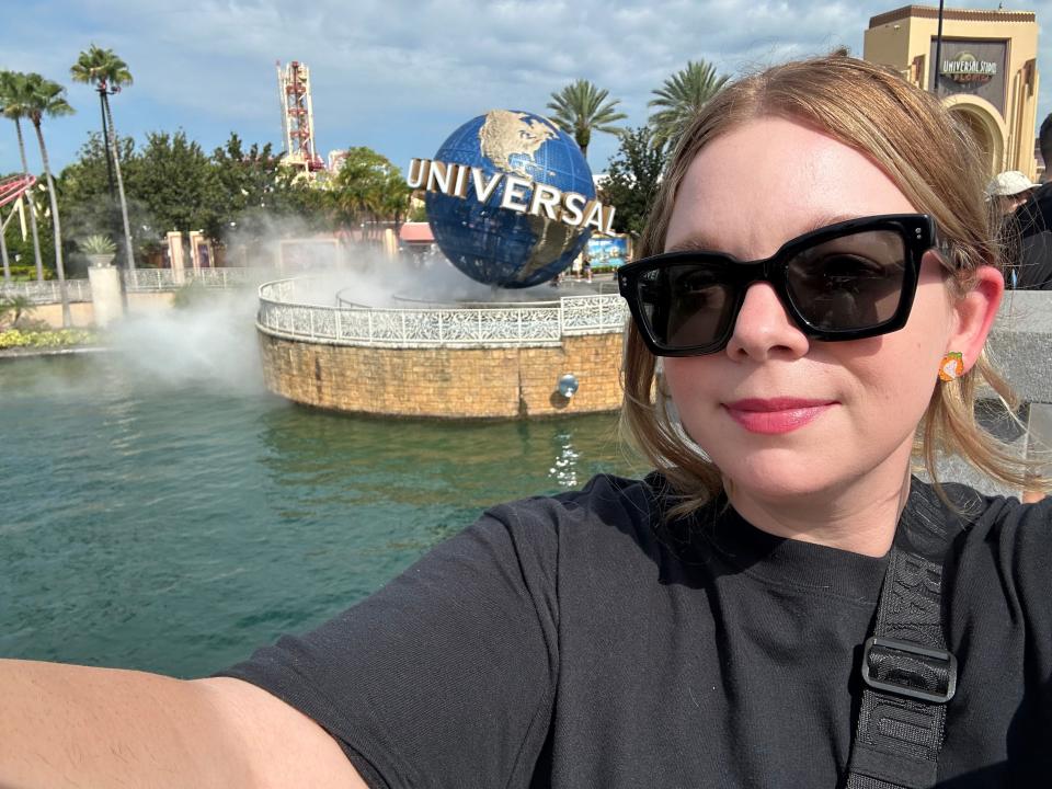 Author Jacqueline Dole taking a selfie in front of the Universal Studios Florida sign. Dole is wearing black sunglasses and a black shirt.