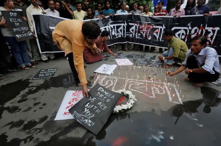 A man places a sign as others light candles during a vigil in Kolkata, India, to show solidarity with the victims of the attack at Holey Artisan restaurant after Islamist militants attacked the upscale cafe in Dhaka, Bangladesh, July 2, 2016. REUTERS/Rupak De Chowdhuri