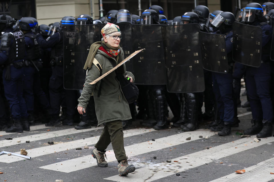 A demonstrator walks by a line of riot police officers during a demonstration, Tuesday, March 7, 2023 in Paris. Demonstrators were marching across France on Tuesday in a new round of protests and strikes against the government's plan to raise the retirement age to 64, in what unions hope to be their biggest show of force against the proposal. (AP Photo/Aurelien Morissard)