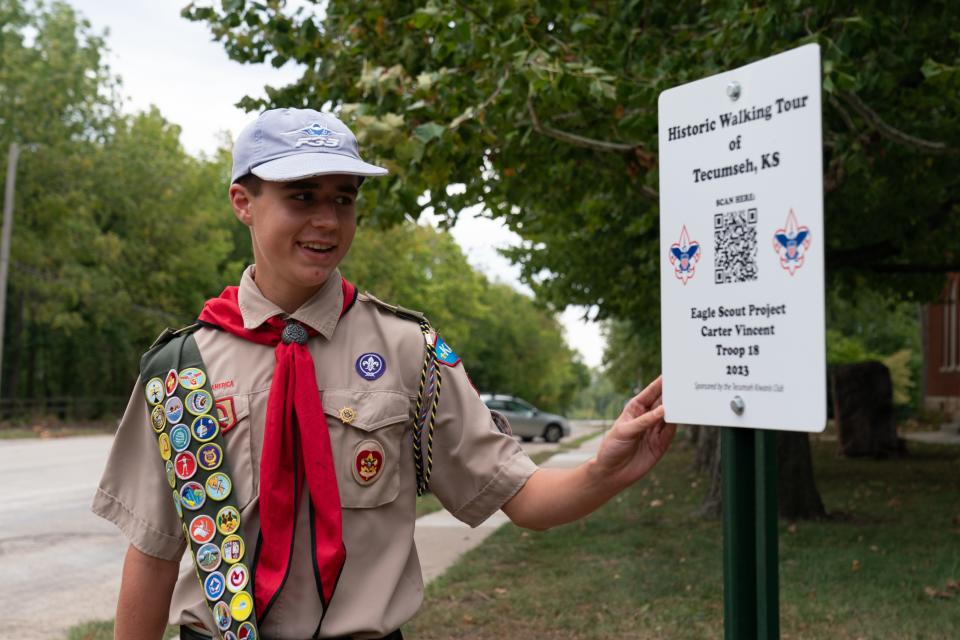 Shawnee Heights freshman Carter Vincent points toward the starting point of his historic walking tour of Tecumseh, where those interested in learning about the town's history can use an interactive QR code to view a digital map of the town.