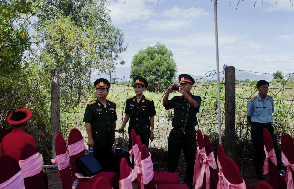 With the backdrop of a field contaminated by dioxin, Vietnamese delegates attend a ceremony marking the start of a project to clean up dioxin left over from the Vietnam War, at a former U.S. military base in Danang, Vietnam Thursday Aug. 9, 2012. The U.S. and Vietnam on Thursday launched a four-year joint effort to clean up dioxin leftover from Agent Orange that was mixed, stored and loaded onto planes at the former U.S. military base, which is now part of Danang’s airport. Dioxin can linger in soils and at the bottom of lakes and rivers for generations, entering the food supply through the fat of fish and other animals. (AP Photo/Maika Elan)