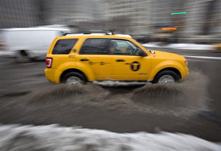 A taxi drives through a huge puddle in the rain in the Manhattan borough of New York February 5, 2014. REUTERS/Carlo Allegri