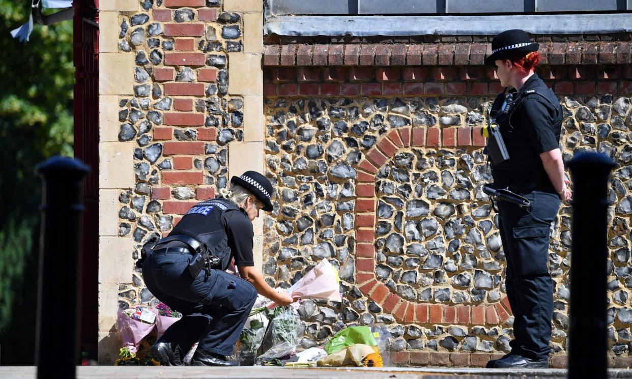<span>A police officer lays flowers, given by a member of the public, at an entrance of Forbury Gardens in Reading in June 2020.</span><span>Photograph: Ben Stansall/AFP/Getty Images</span>