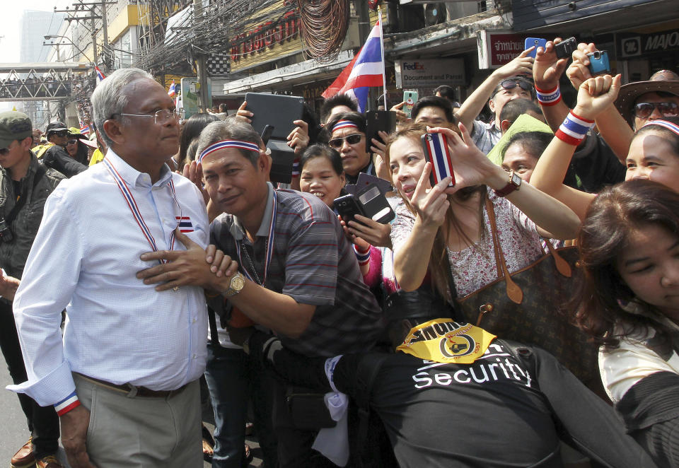 Thai anti-government protest leader Suthep Thaugsuban, left, is greeted by his supporters during a march in Bangkok, Thailand, Saturday, Jan. 25, 2014. Thailand's ruling party has questioned the reasoning behind a court decision allowing next month's general election to be postponed, but held open the possibility that it might agree to put off the polls if its political rivals agree to recognize the legitimacy of a new vote. (AP Photo/Apichart Weerawong)