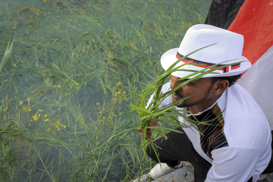 Oromos throw grass and flowers into a pool of water as they celebrate the annual Irreecha festival in the capital Addis Ababa, Ethiopia Saturday, Oct. 2, 2021. Ethiopia's largest ethnic group, the Oromo, on Saturday celebrated the annual Thanksgiving festival of Irreecha, marking the end of winter where people thank God for the blessings of the past year and wish prosperity for the coming year. (AP Photo)