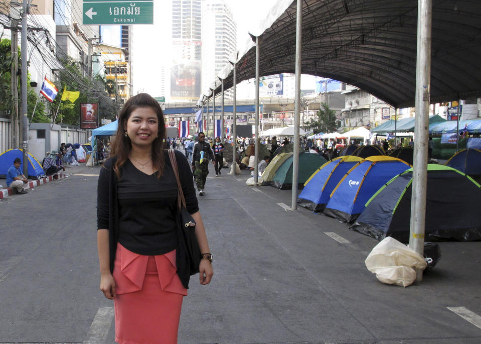 In this photo taken January 14, 2014, Chanida Wongpeam, 27, an office worker, poses for a photo by tents for anti-government protesters near a rally site in one of the major business districts in Bangkok, Thailand. "It’s frustrating to be a person in the middle ground. I wanted to believe in one side but then I looked the other way, the other side is also right in what they do. Plus, they are all corrupted. That’s universal. The only difference is just how much or how little they corrupt," Chanida said. "Really I want them to talk to find a way to end this as soon as possible. Thailand is going nowhere because of this.” (AP Photo/Thanyarat Doksone)