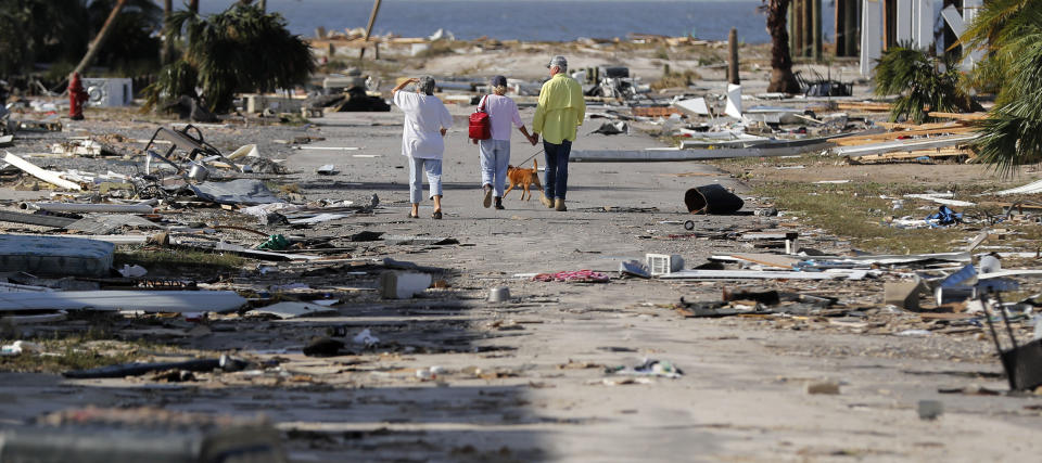 People hold hands as they walk amidst destruction in the aftermath of Hurricane Michael in Mexico Beach, Fla., Thursday, Oct. 11, 2018. (AP Photo/Gerald Herbert)