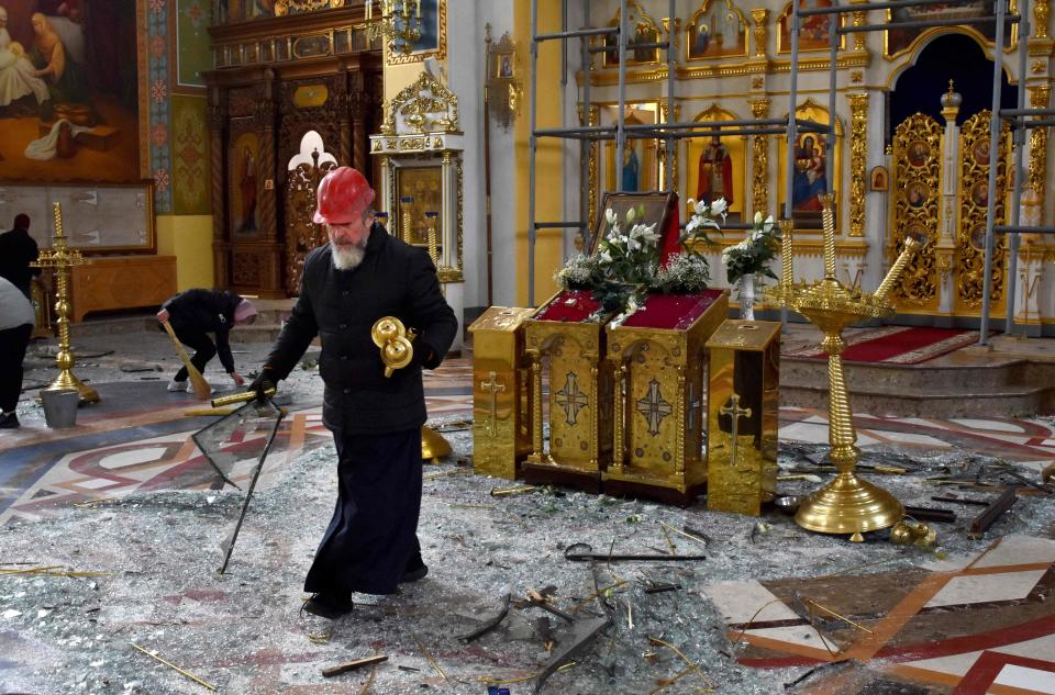 An Orthodox priest collects religious objects as others clear up glass and debris inside the Holy Intercession Cathedral damaged after missile strikes in Zaporizhzhia on Oct. 18, 2023, amid the Russian invasion of Ukraine. 
(Credit: ANDRIY ANDRIYENKO, AFP via Getty Images)