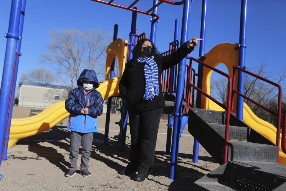 Angel, 6, and his mother Angelica Rodriguez walk in a playground in front of their house on Wednesday, Dec. 23, 2020, in Santa Fe, N.M. Rodriguez pointed to a park that's closed due to virus restrictions. Rodriguez and her husband, both cooks, struggled to pay rent this year as their hours were cut in half. (AP Photo/Cedar Attanasio)