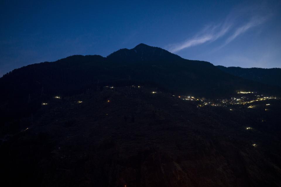 Lights from a remote village are visible above the Nathpa-Jhakri dam in the Kinnaur district of the Himalayan state of Himachal Pradesh, India, Sunday, March 12, 2023. The remote region amid gigantic peaks in the Himalayas is home to just 100,000 people but makes four nuclear power plants worth of energy. (AP Photo/Ashwini Bhatia)