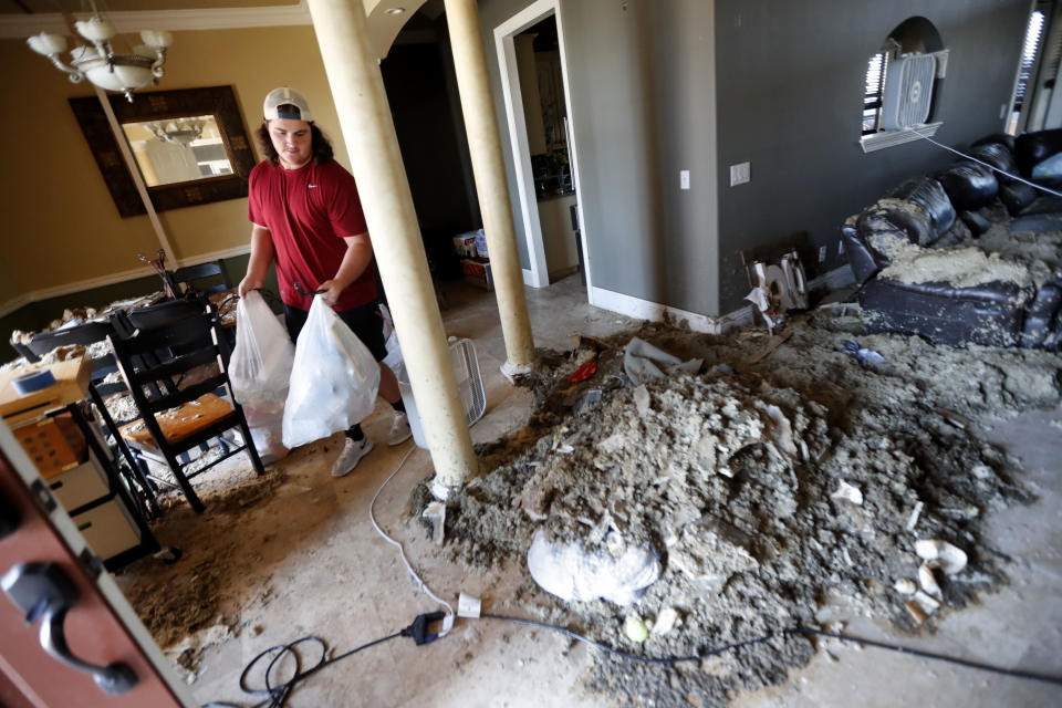 Castor Gay, who plays center for the Mosley High football team, cleans debris from his heavily damaged home, in the aftermath of Hurricane Michael in Lynn Haven, Fla., Friday, Oct. 19, 2018. (AP Photo/Gerald Herbert)