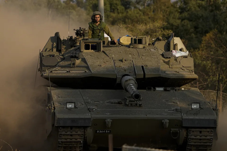 Israeli soldier drive a tank to a staging area near the border with Lebanon, Wednesday, Oct. 11, 2023. An Israeli ground offensive in Gaza would further escalate the war raging since Hamas launched its unprecedented attack days ago. The United States already deployed one aircraft carrier group to the region, with another on the way. That reflects concerns of a widening conflict and is meant to deters Iran and others. (AP Photo/Ariel Schalit)