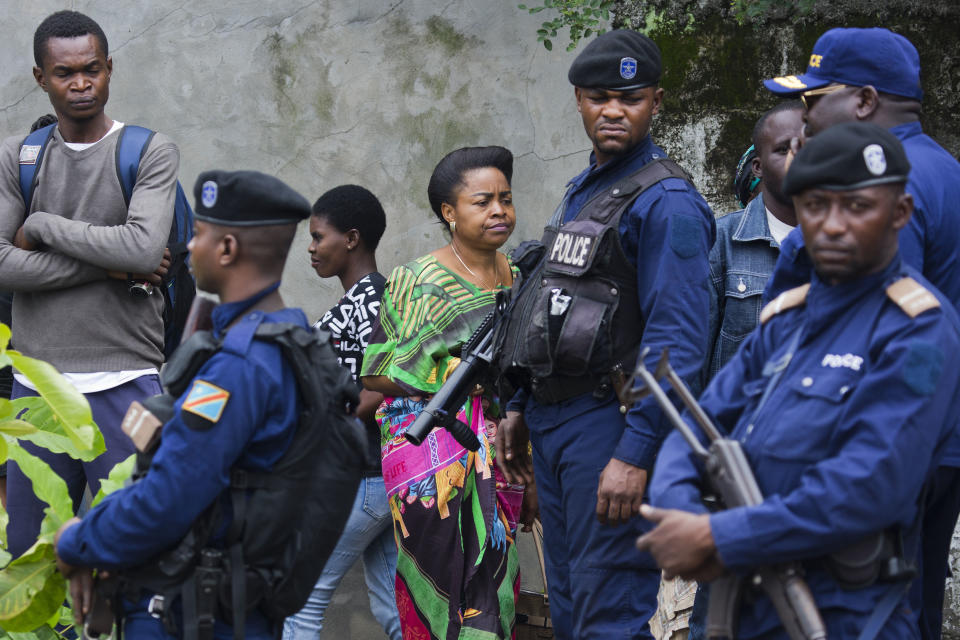 Congolese voters walk past police as they reach the St. Raphael school in the Limete district of Kinshasa Sunday Dec. 30, 2018 to cast their ballot. Forty million voters are registered for a presidential race plagued by years of delay and persistent rumors of lack of preparation. (AP Photo/Jerome Delay)
