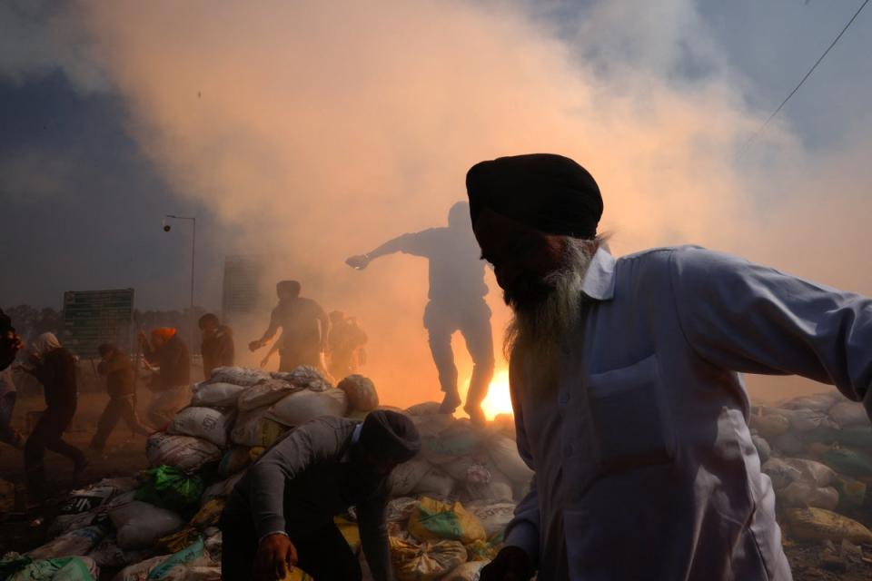 Farmers, who are marching towards New Delhi to press for better crop prices promised to them in 2021, run for cover amidst tear gas fired by police to disperse them at Shambhu barrier, a border crossing between Punjab and Haryana states, India, 21 February 2024 (Reuters)