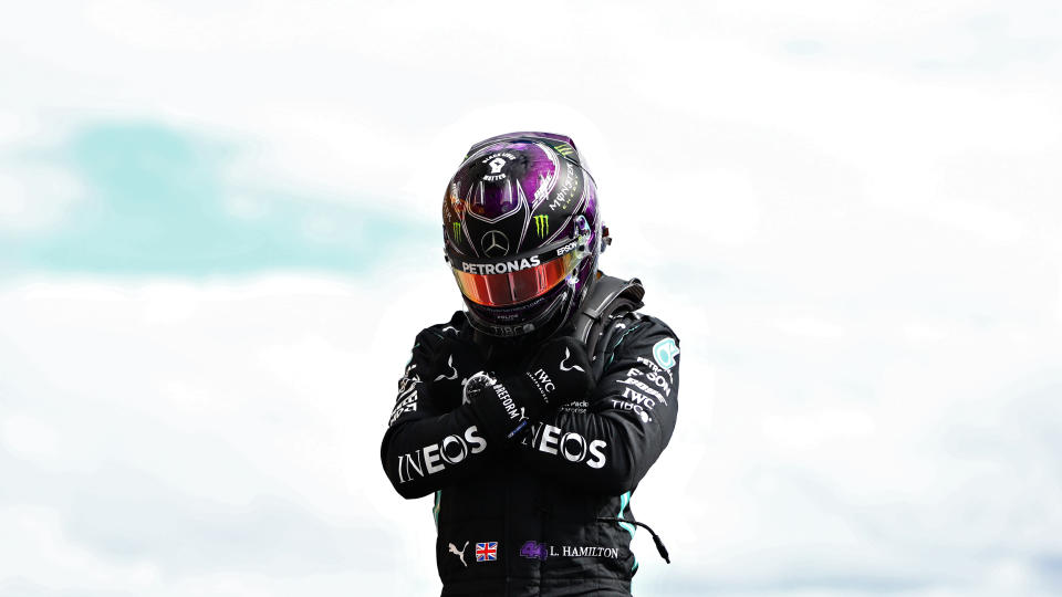 Lewis Hamilton poses with 'Wakanda Forever' on top of his Mercedes.