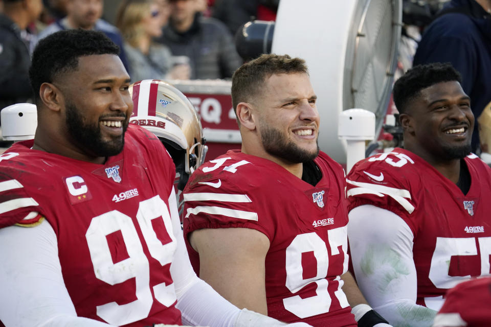 San Francisco 49ers defensive tackle DeForest Buckner (99) smiles as he rests on the bench with defensive end Nick Bosa (97) and defensive end Dee Ford (55) during the second half of an NFL divisional playoff football game against the Minnesota Vikings, Saturday, Jan. 11, 2020, in Santa Clara, Calif. (AP Photo/Tony Avelar)