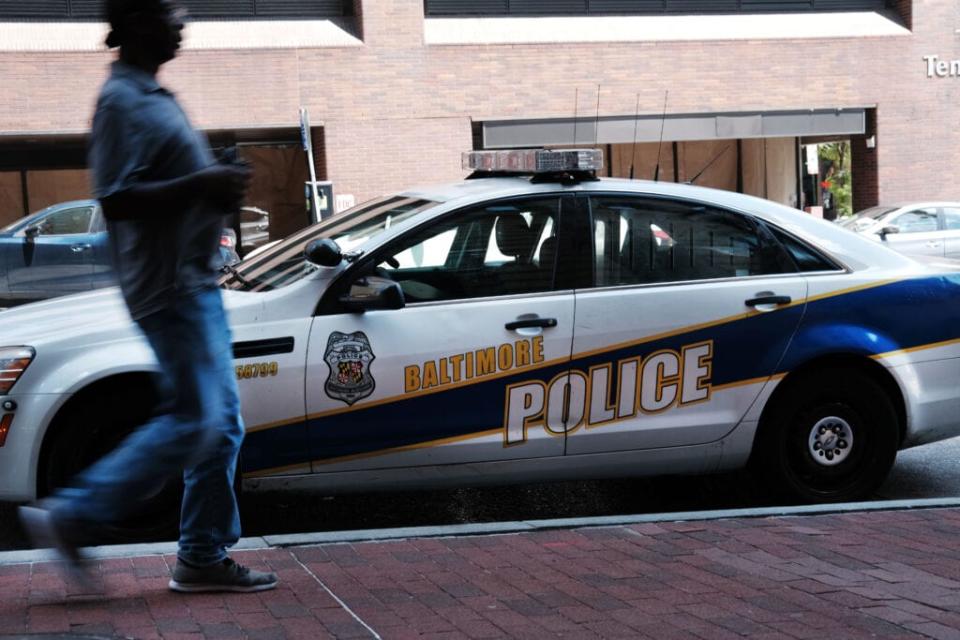 A person walks past a police car on July 28, 2019 in Baltimore, Maryland. (Photo by Spencer Platt/Getty Images)