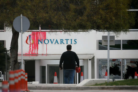 A worker walks in front the entrance of the Swiss drugmaker Novartis offices after protesters threw paint and smashed windows, in Athens, Greece, February 25, 2018. REUTERS/Costas Baltas