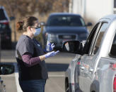 An employee gives instructions for self-administering a COVID-19 test in the parking lot at Primary Health Medical Group's clinic in Boise, Idaho, Tuesday, Nov. 24, 2020. The urgent-care clinic revamped into a facility for coronavirus patients as infections and deaths surge in Idaho and nationwide. Some 1,000 people have died due to COVID-19, and infections this week surpassed 100,000. (AP Photo/Otto Kitsinger)