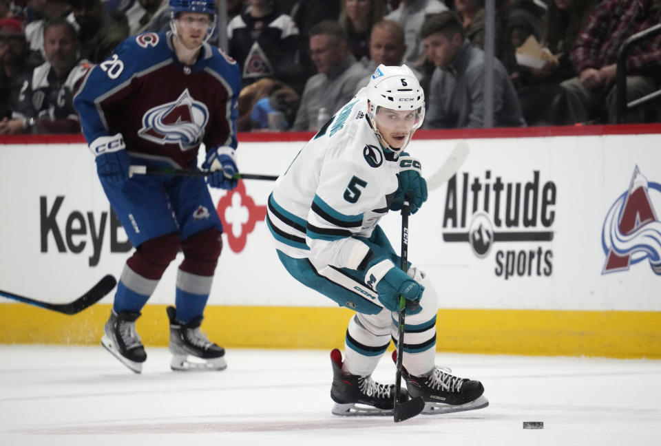 San Jose Sharks defenseman Matt Benning, front, collects the puck in front of Colorado Avalanche center Lars Eller in the third period of an NHL hockey game Tuesday, March 7, 2023, in Denver. (AP Photo/David Zalubowski)