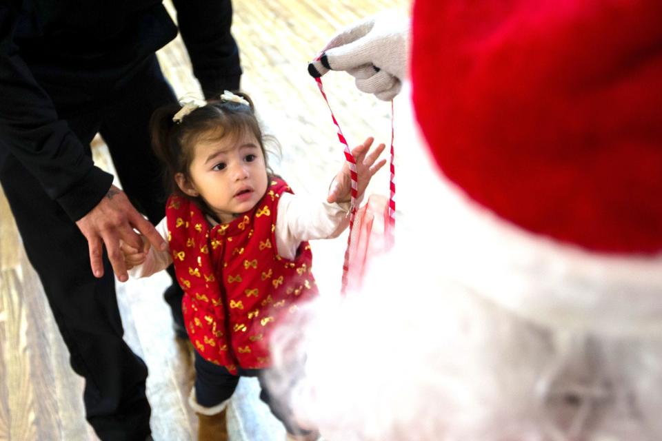 CHIEFTAIN PHOTO/MATT WEIGAND Devyn Baker, 2, reaches for a stocking from Santa Friday during Mama's Christmas Stocking Giveaway, that honors the late Mary 'Mama' Jaramillo.