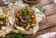 Der Lammschmortopf Kleftiko ist als typisches Landesgericht vor allem auf der Insel Zypern bekannt. Dafür werden kleine Lammfleischstücke mit Zwiebeln, Knoblauch, Kartoffeln, Zucchini, Oliven, Tomaten, Feta, Rosmarin und Oregano mit Backpapier zu Päckchen gepackt und in eine Auflaufform gelegt. Nach 90 Minuten Garzeit sind die Pakete essfertig. (Bild: iStock / fazeful)