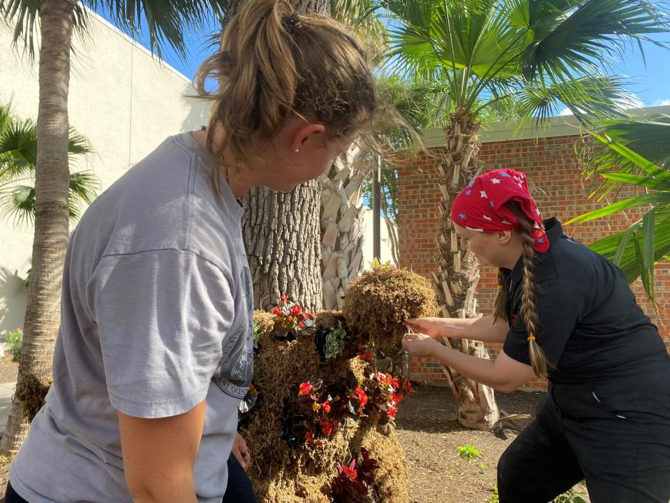 Kathryn Chambers, 21, left, and professor April Terra Livingston  add the finishing touch to a living sculpture of a Texas rattlesnake at Texas A&M University-Corpus Christi on Thursday, April 28, 2022.