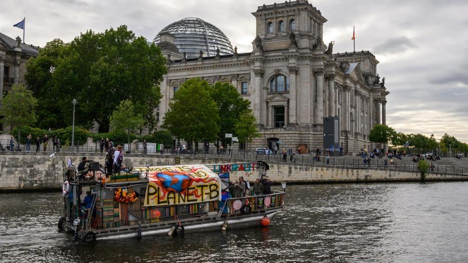 Demonstranten fahren mit einem Boot am Berliner Reichstagsgebäude vorbei. Das Klimapaket der Bundesregierung wird von Opposition, Umweltschützern und Wirtschaftsverbänden weiter scharf kritisiert. Foto: Christophe Gateau