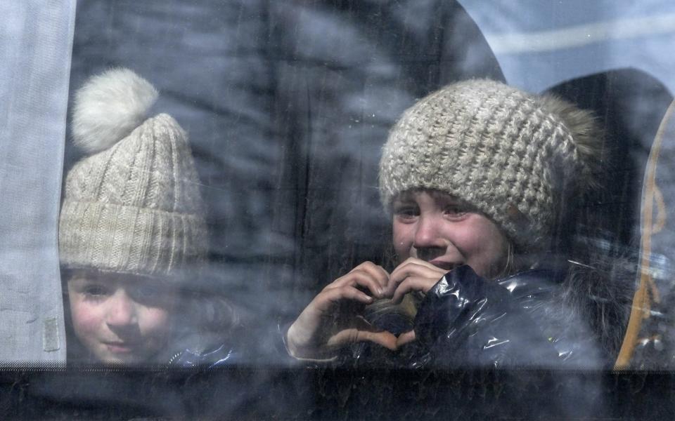 A little girl makes hearth shape with her hands as civilians are being evacuated along humanitarian corridors from the Ukrainian city of Mariupol -  Stringer/Anadolu Agency via Getty Images