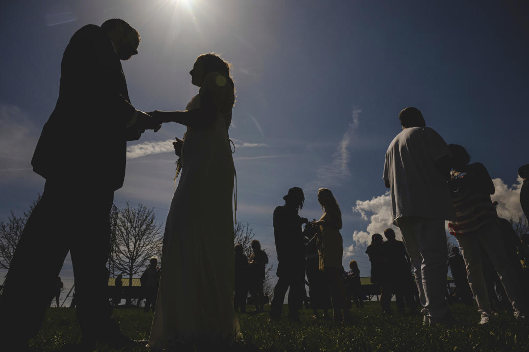 Couples hold hands outside as they wed during a solar eclipse in Trenton, Ohio.