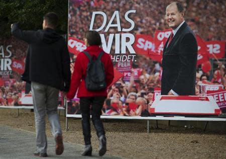 People walk past an election campaign poster of Peer Steinbrueck, the chancellor candidate of the Social Democratic Party (SPD), in Berlin, September 12, 2013. REUTERS/Thomas Peter