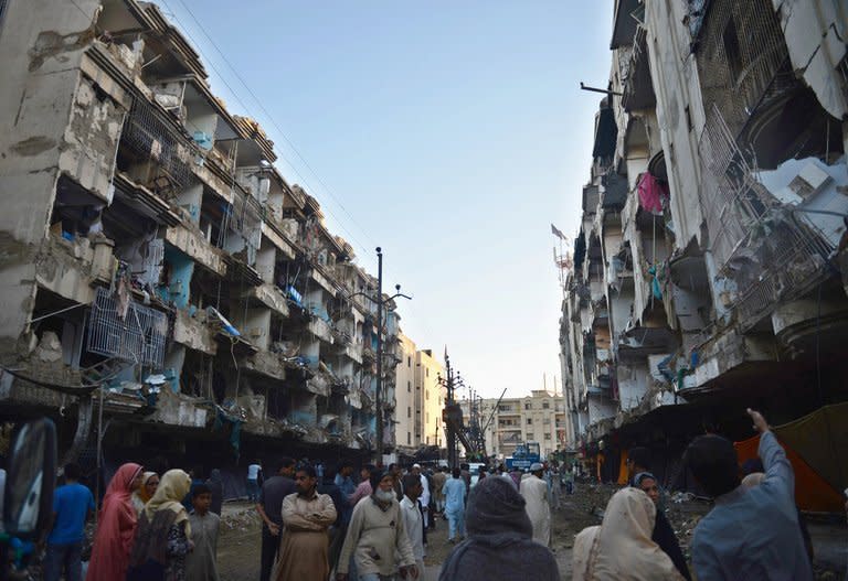 People gather outside their damaged homes in Karachi on March 4, 2013. Thousands of Pakistanis have attended funerals for victims of a bombing that killed 48 people in a Shiite Muslim area of Karachi, the latest in a series of devastating attacks ahead of elections