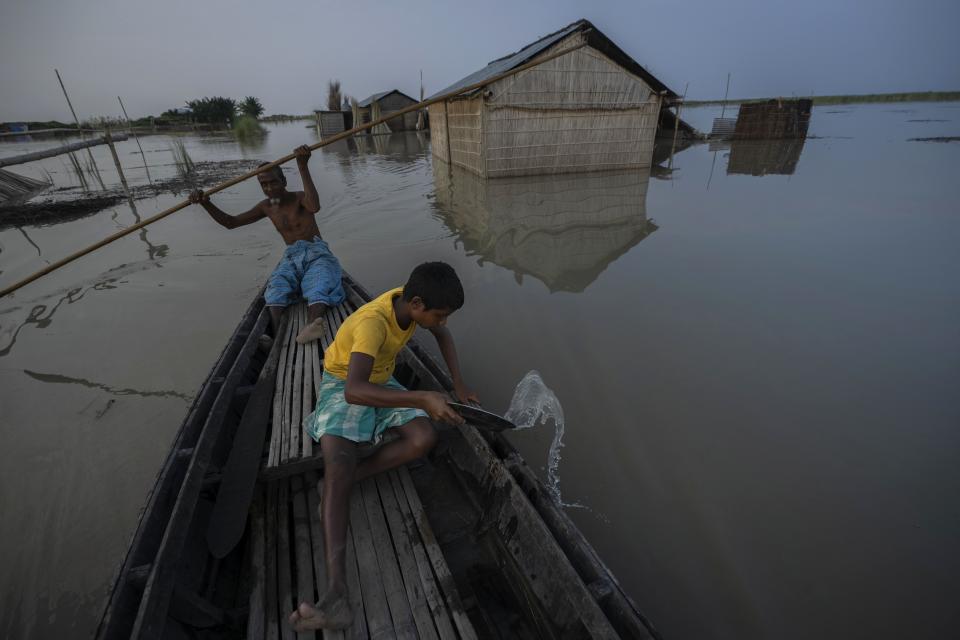 Yaad Ali, 55, left, and his son Musikur Alam, 14, row a boat in the floodwaters in Sandahkhaiti, a floating island village in the Brahmaputra River in Morigaon district, Assam, India, Tuesday, Aug. 29, 2023. (AP Photo/Anupam Nath)