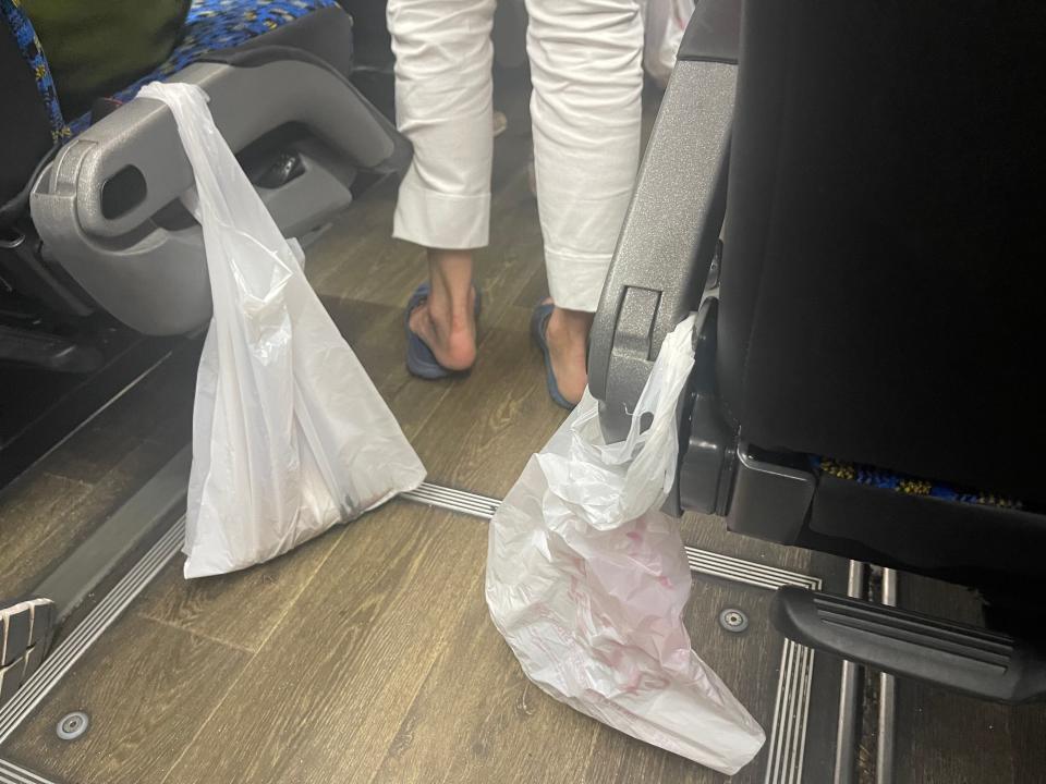 Two garbage bags hanging on the end of bus seats on a coach bus