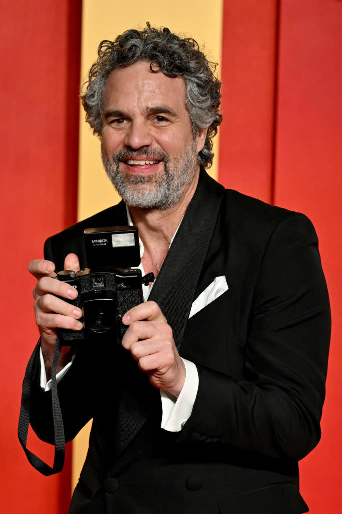 Man in a suit with camera smiling. (Person's name not provided for privacy compliance.)