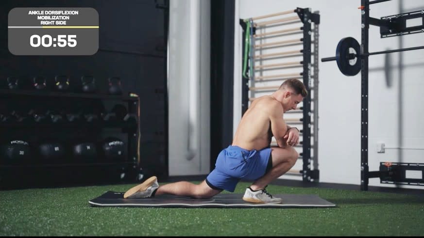 Noah performing a knee stretch in a half lunge position with elbows on right knee during stretch on yoga mat