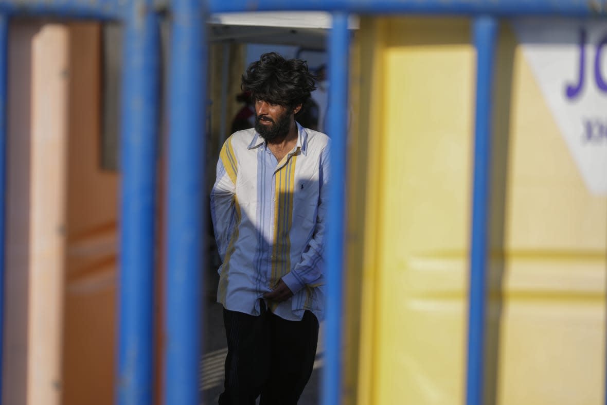 A survivor of a shipwreck walks outside a warehouse at the port in Kalamata town, about 240 kilometers (150 miles) southwest of Athens, Wednesday, June 14, 2023. (AP Photos/Thanassis Stavrakis)