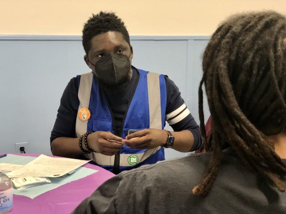 Oluwasegun Abe discusses the vaccine process with Eli Muhammad, 21, at a LouVax clinic at Shawnee Community Center on Thursday,  Jan. 13, 2022.