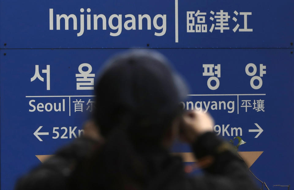 A woman takes a photo in front of a signboard showing the distance to North Korea's capital Pyongyang and to South Korea's capital Seoul from Imjingang Station in Paju, South Korea, Saturday, Nov. 24, 2018. South Korea said Saturday that the United Nations Security Council granted an exemption to sanctions that will allow surveys on North Korean railroad sections the Koreas want to connect with the South. (AP Photo/Lee Jin-man)